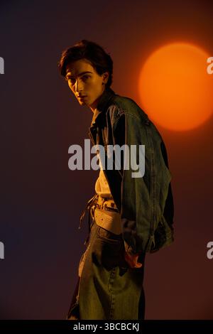 Eine junge, modische, nicht binäre Person steht während des Sonnenuntergangs selbstbewusst und zeigt einen einzigartigen Stil. Stockfoto