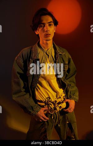 Junge nicht-binäre Person zeigt Stil und Selbstvertrauen in einer künstlerischen urbanen Kulisse während der Dämmerung. Stockfoto