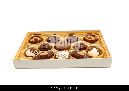 Gemischte Schokoladenbox isoliert auf weißem Hintergrund. Elegante Auswahl an Pralinen in einer goldenen Schachtel. Verschiedene Formen, Farben und Füllungen laden Sie ein Stockfoto