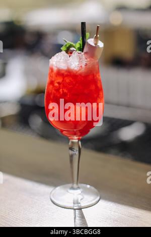 Erfrischendes rotes Cocktailgetränk. Kaltes Getränk im Weinglas. Zerstoßenes Eis mit Garnitur. Sommerparty Alkohol. Präsentation der Bartheke. Tropischer Geschmack. Stockfoto