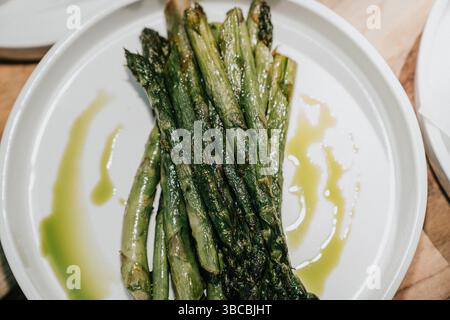 Ein Teller grüner Spargel mit grüner Sauce. Die Spargel werden in kleine Stücke geschnitten und ordentlich angeordnet. Die Soße wird über die getränkt Stockfoto