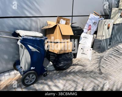 Unsachgemäß entsorgte Siedlungsabfälle, Kartons und Plastiktüten stapeln sich neben einem modernen Geschäftsgebäude Stockfoto
