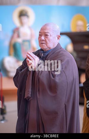 Ein älterer buddhistischer Mönch in schwarz-braunen Gewändern bei einem Quinming-Gottesdienst zu Ehren des Verstorbenen. Im Chuang Yen Kloster in Carmel, Upstate New York. Stockfoto