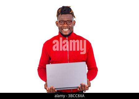Hübscher junger Mann mit rotem Pullover und Laptop, während er lächelt. Stockfoto