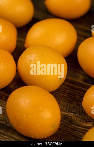 Feuchte Tomaten kleiner Größe mit weichem Fleisch, gelbe Tomaten mit Tropfen Wasser bedeckt Stockfoto