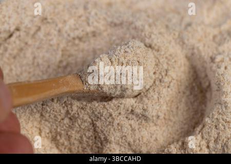 Natürliches Vollkornmehl mit Kleie, frisches Weizenmehl in Nahaufnahme, Mehl zur Brotherstellung mit Kleie, Mehl mit einem Holzlöffel Stockfoto