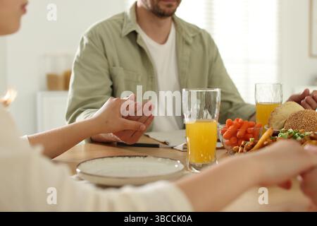 Familie betet zusammen vor dem Abendessen am Tisch drinnen, Nahaufnahme Stockfoto