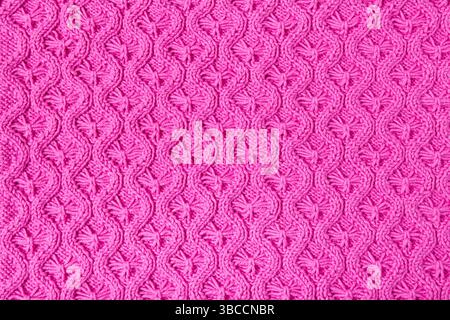 Gestrickter rosafarbener Hintergrund. Großes Strickmaterial mit Muster. Nahaufnahme einer gestrickten Decke Stockfoto