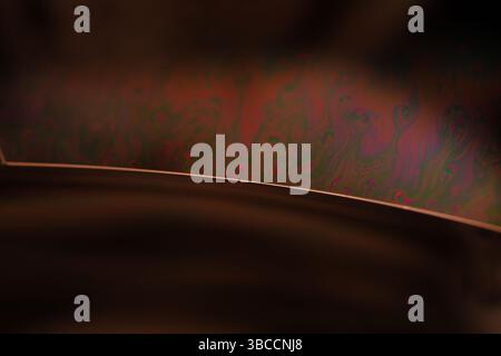 Grüne Flüssigkeitsoberfläche, grüne Reflexionen der Flüssigkeit in Makro, Blasen in Makro, Verbindung von Blasen in Makro, Zelle aus Flüssigkeit, dunkler Hintergrund Stockfoto