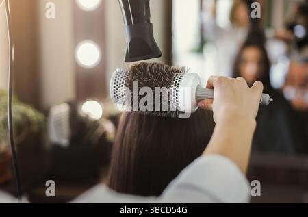 Kosmetikerin, die das Haar der Frau trocknet Stockfoto