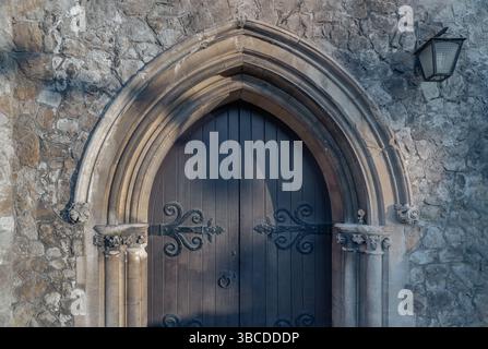 Royal Tunbridge Wells, Großbritannien - 29. April 2025 - Detail der alten gotischen mittelalterlichen Kirche, Holztür und Sandsteinbögen mit dekorativem Schmiedeeisen Stockfoto