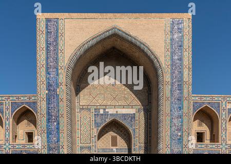 Hohe Bögen und geometrische Fliesen schmücken die Fassade der Ulugbek Madrasah in Buchara, Usbekistan, ein Meisterwerk der Timuriden-Architektur. Stockfoto