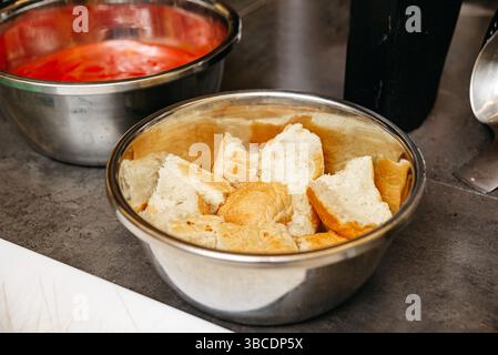 Stücke von frischem weißem Brot in einer Edelstahlschale, die wahrscheinlich für ein Koch- oder Backrezept zubereitet wird. Stockfoto