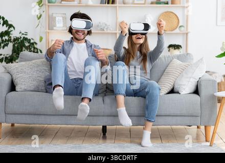 Emotionale junge Familie spielt Videospiele im Wohnzimmer Stockfoto