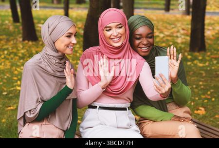 Drei Muslimische Damen Videoanrufe Winken Hallo Zu Smartphone Im Freien Stockfoto