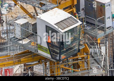 DANANG, VIETNAM, 25. APR 2025, Nahaufnahme einer Turmkrankabine mit einem Kranfahrer über einer stark befahrenen Baustelle. Stockfoto