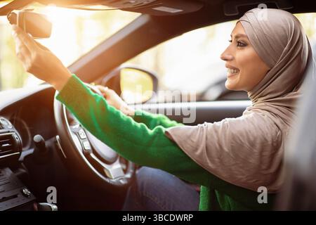 Glücklich muslimische Frau fahren allein Einstellung Rückspiegel Stockfoto