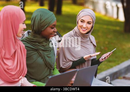 Muslimische Frau Zeigt Freunden Smartphone Und Empfiehlt Anwendung Im Freien Stockfoto