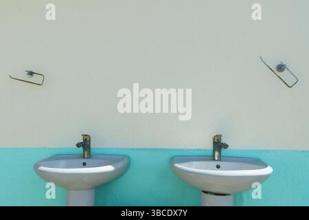 Ein Hintergrund die grobe Struktur einer alten zweifarbigen Putzwand mit Handwaschhähnen Stockfoto