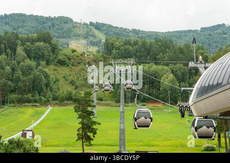 Manzherok Resort, Russland. Sesselliftkabine im Hintergrund von Bergen und Wäldern. Seilbahnfahrt zu Aussichtspunkten in den Bergen. Stockfoto