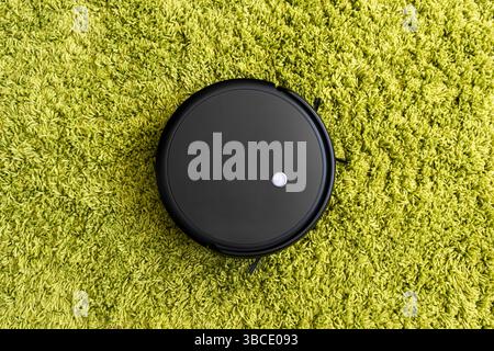 Roboter-Staubsauger auf dem Boden, Smart Roboter automatisieren drahtlose Reinigungstechnik Maschine im Wohnzimmer. Reinigung flauschigen Teppich mit einer automatischen va Stockfoto