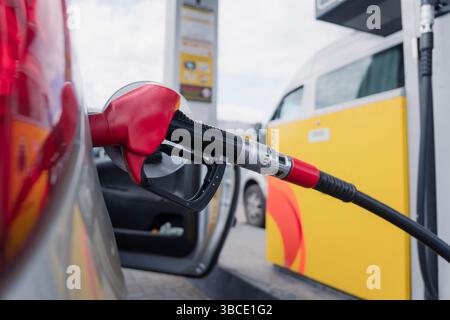 Eine Tankpistole weckt ein graues Auto an einer Tankstelle. Anstieg des Benzinpreises. Stockfoto