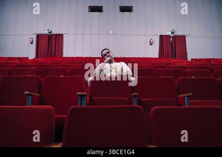 Ein einsamer Zuschauer in einem leeren Theater beobachtet aufmerksam das Stück Stockfoto