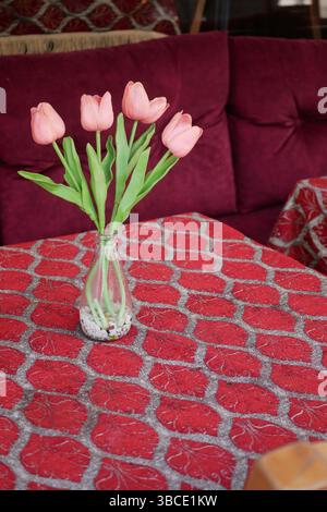 Pinkfarbene Tulpen in einem gemütlichen Café mit lebhaftem Tisch Stockfoto