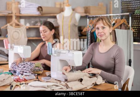 Weibliche Modedesignerinnen nähen individuelle Kleidungsstücke an Automaten im Studio Stockfoto
