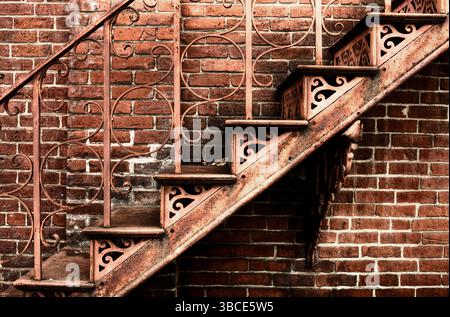 Rostiges schmiedeeisernes Treppenhaus gegen rote Backsteinmauer Stockfoto