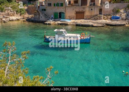 Blaues und weißes Fischerboot, das im azurblauen Wasser von cala Figurera verankert ist Stockfoto