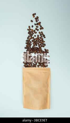 Papiertüte zur Abgabe von Kaffeebohnen auf blauer Oberfläche, von oben für Präsentationen im Einzelhandel oder bei Verpackungen Stockfoto