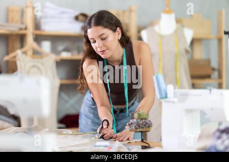 Weibliche Modedesignerin schneidet Stoff in Musterstücke Stockfoto
