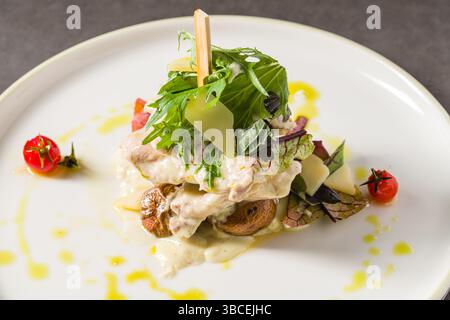 Gegrilltes Hühnchen mit Pilzen und Sahnesauce auf einem dunklen Steintisch Stockfoto