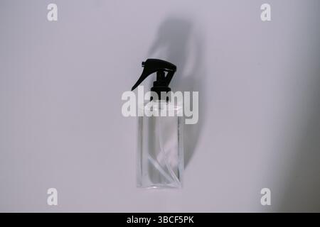 Eine einfache, durchsichtige Sprühflasche mit schwarzem Auslöser, die vor einem weißen Hintergrund sitzt und perfekt für Reinigungs- oder Kosmetikprodukte geeignet ist. Stockfoto
