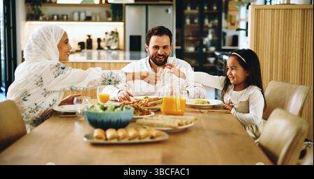 Muslime, Eltern und Kind mit Essen im Haus für Eid-Mittagessen, gesunde Mahlzeit und Festmahl zum Feiern. Mutter, Servieren und Familiengericht für die Ernährung Stockfoto