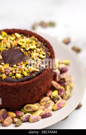Dubai Schokoladen-Käsekuchen mit verstreuten Pistazien auf Keramikplatte aus nächster Nähe Stockfoto