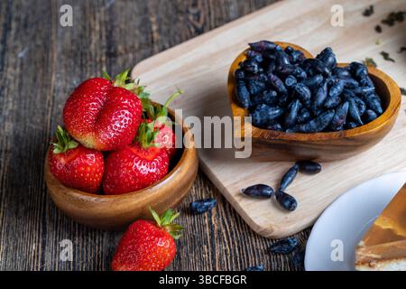 Geißelbeeren in einem Holzteller, reife gesunde Geißelbeeren auf dem Küchentisch Stockfoto