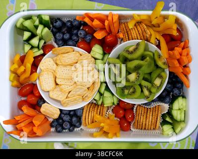 Bunte Partyteller mit Crackern, Karotten, Gurken, Paprika, Tomaten, Heidelbeeren und Kiwi. Ein perfekter gesunder Snack für jede Veranstaltung Stockfoto