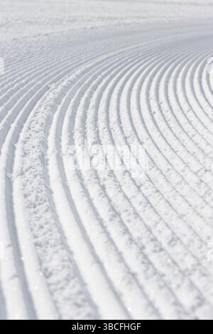 Nahaufnahme dynamischer gekrümmter Linien in weißem, schneestrukturiertem Hintergrund Stockfoto