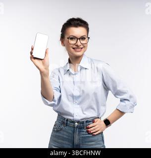 Geschäftsfrau, die auf einen leeren Smartphone-Bildschirm zeigt, um Werbung oder Mockup zu machen und Professionalität und Innovation zu zeigen, isoliert auf den Witz Stockfoto