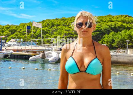 Junge blonde Frau in blauem Badeanzug badet in der Adria am Palmizana Beach Stockfoto