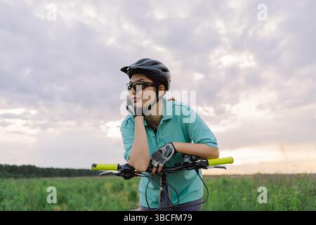 Frau mit Helm und Sonnenbrille fährt Fahrrad im Freien Stockfoto
