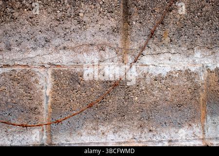 Alte, rostige Barbettdraht hängt über einer grauen Zementwand Stockfoto