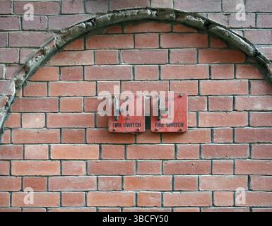 Zwei alte rote Metallbrandschalter an einer Backsteinwand im Außenbereich Stockfoto