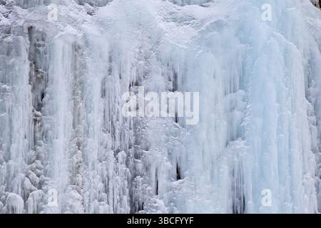 Die Textur blauer Eiszapfen auf eisigen Felswänden Stockfoto