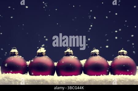 Alte gebrauchte rote Christbaumkugeln mit Schnee auf einem dunklen Hintergrund Stockfoto