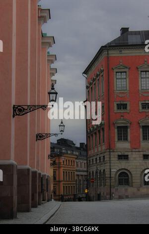 Leere Kopfsteinpflasterstraße in Stockholms Altstadt (Gamla Stan), umgeben von pastellfarbenen historischen Gebäuden an einem bewölkten Herbsttag, Schweden. Stockfoto