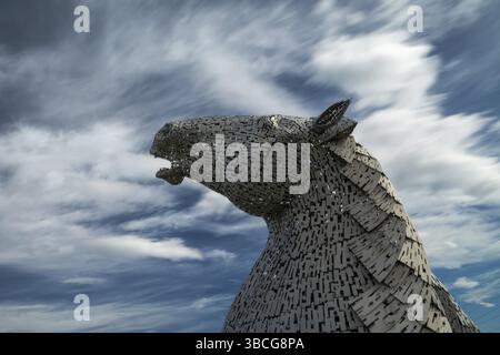 Falkirk, Vereinigtes Königreich - 20. Juni 2022: Eine der Kelpies-Pferdekopfskulpturen mit einem ausdrucksstarken, langbelichteten Himmel dahinter Stockfoto