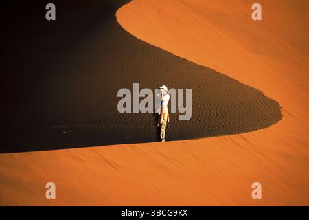 Frau, die auf dem Dünenwappen steht und Fotos macht, Sossousvlei, Namib-Wüste, Namibia, Afrika Stockfoto